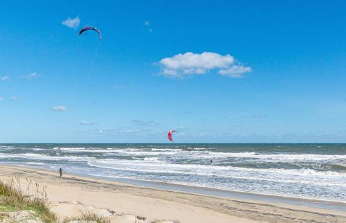 a person is flying a kite on the beach at Dune Diamond - Nags Head MP 16.5, Oceanfront, Elevator, Heated Pool, Hot Tub, Pets OK, Flex Stays in Nags Head