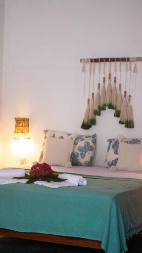 a bed with a green blanket and flowers on it at Vila Manguita Suíte Manguita in São Gonçalo do Amarante