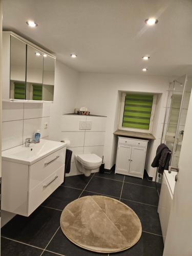 a white bathroom with a toilet and a sink at Ferienwohnung Quierschied in Quierschied
