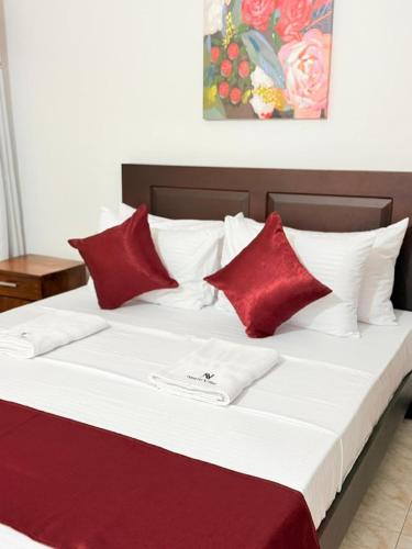 a large bed with red and white pillows on it at Nishi Villa in Negombo