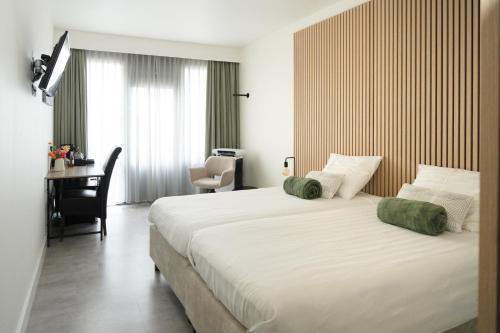 a bedroom with a large white bed and a desk at Auberge De Moerse Hoeve in De Moer