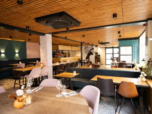 a restaurant with wooden ceilings and tables and chairs at Auberge De Moerse Hoeve in De Moer