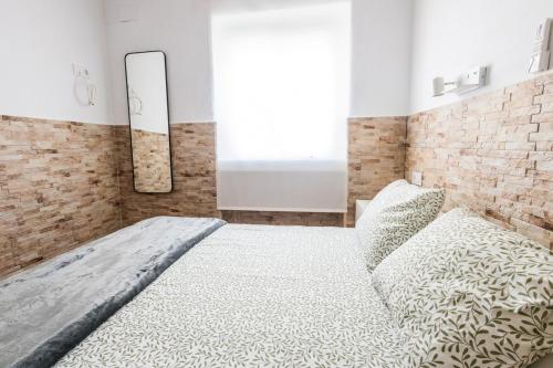a bedroom with a large bed and a brick wall at GuestReady - Calvario Rota 30 JC in Rota