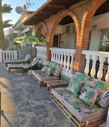 an outdoor patio with couches and umbrellas on a house at Villa Don Giovanni Fuengirola, Piscina Privada y vistas al mar y a la Montaña in Fuengirola