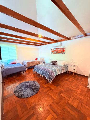 a large room with two beds and a rug at Casa Las Condes, steps from Manquehue Metro in Santiago