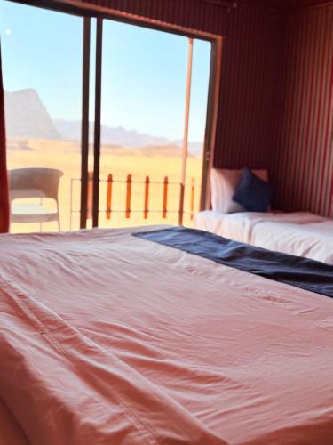 a bedroom with two beds and a large window at Luxury Camp Wadi Rum in Disah