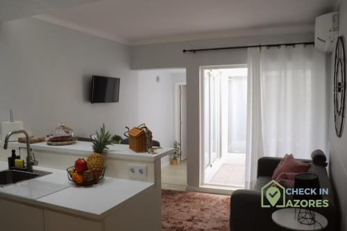 a kitchen and a living room with a sink and a table at Cantinho da Bea Guest House in Angra do Heroísmo