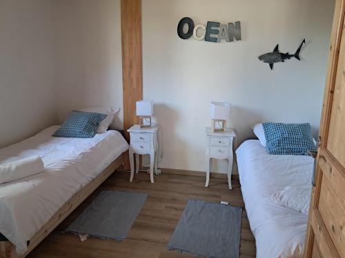 a bedroom with two beds and two night stands at Le Chalet d'Isabelle-sur la vélodyssée-drap-serviette in Sainte-Eulalie-en-Born