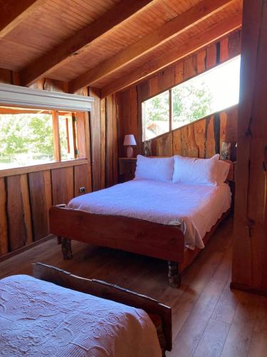 a bedroom with two beds in a log cabin at Kumewe Lodge & Cabañas in Panguipulli