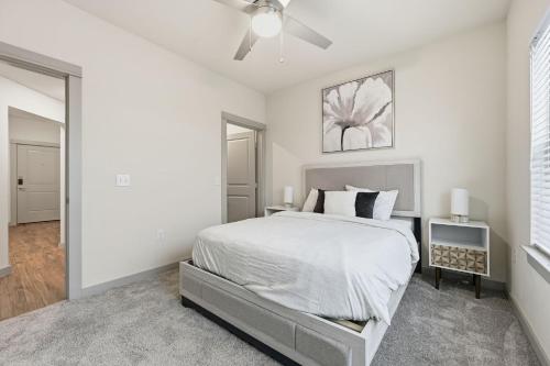 a white bedroom with a bed and a ceiling fan at Unit 232 Comfy 2BR 2BA Retreat in Cleburne