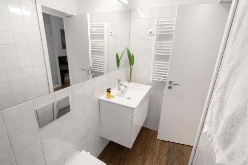 a white bathroom with a sink and a mirror at Oporto City View - Santa Catarina in Porto