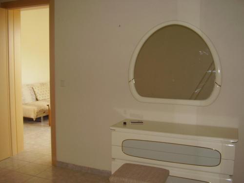 La salle de bains est pourvue d'un miroir au-dessus d'une commode blanche. dans l'établissement Pantelios Village, à Kateliós