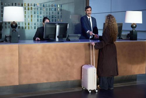 a woman with a suitcase standing at a reception desk at Radisson Blu Hotel, London Canary Wharf East in London