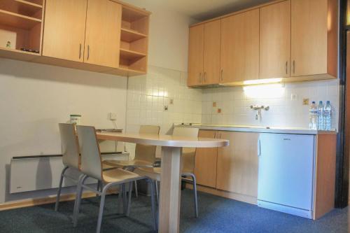 una cucina con tavolo, sedie e frigorifero di Apartments Rogla a Zreče