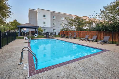 a swimming pool with chairs and a building in the background at Candlewood Suites Hot Springs by IHG in Hot Springs