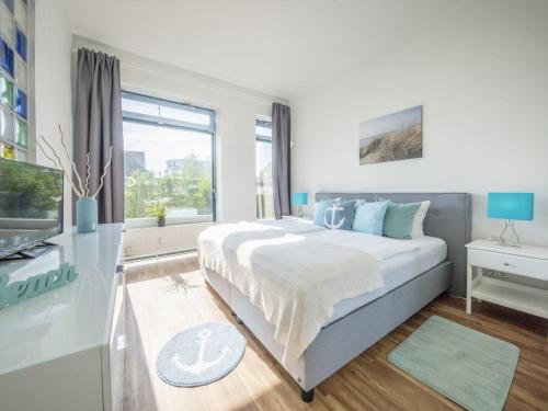 a white bedroom with a large bed and a window at Strandburg "Aquamarin" 01 a in Burgtiefe auf Fehmarn 