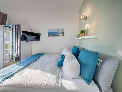 a bedroom with a bed with blue and white pillows at Strandburg "Tiefblau" 01 b in Burgtiefe auf Fehmarn 