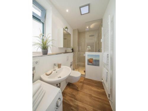 a white bathroom with a sink and a toilet at Strandburg "Azurblau" 01 c in Burgtiefe auf Fehmarn 