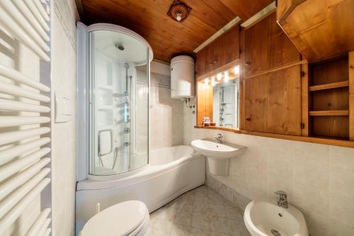 a bathroom with a sink and a tub and a toilet at Villa Cristallino -Stayincortina in Cortina dʼAmpezzo