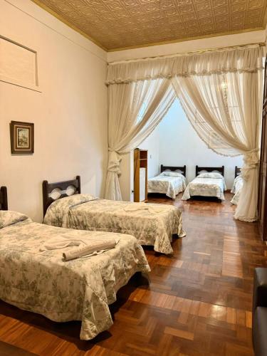 a bedroom with three beds and a window at Hotel Priskar in Ouro Preto