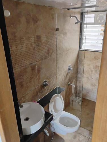 a bathroom with a toilet and a sink and a shower at Sylevo 2bhk Baner in Pune