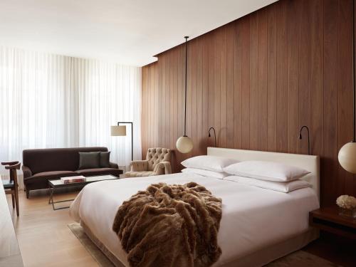a bedroom with a large white bed and a chair at The London EDITION in London