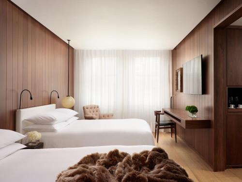 a hotel room with two beds and a desk at The London EDITION in London