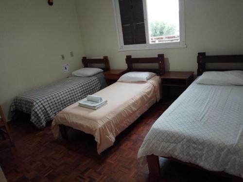 a room with three beds and a window at Cyro Palace Hotel Ltda in Caçapava do Sul