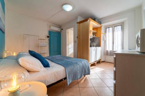 a bedroom with a bed with blue pillows and a kitchen at Azure Comfort Studio in Bellagio