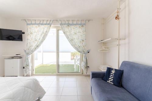 a living room with a blue couch and a large window at Una Terrazza sul Mare The Lighthouse in Paola