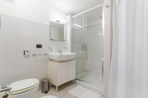 a white bathroom with a sink and a shower at Una Terrazza sul Mare The Lighthouse in Paola