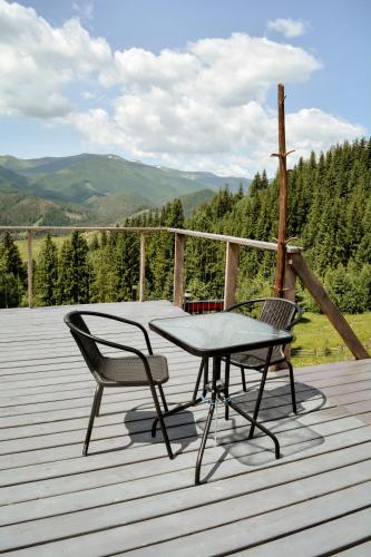 a table and two chairs on a wooden deck at Motyl Glamping Resort in Dzembronya