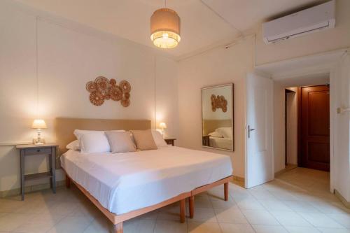 a bedroom with a large white bed and a mirror at Beach Lake Apartment in Bellagio