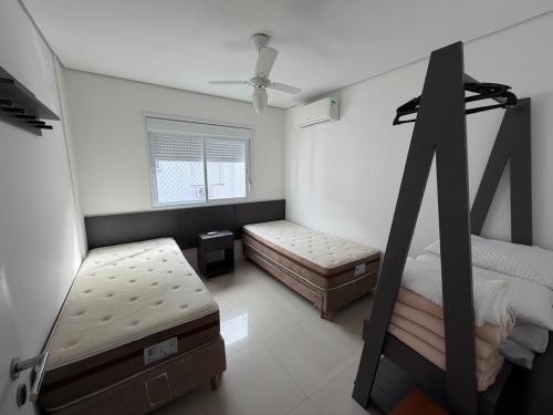 a bedroom with two beds and a window at Ed. Mauí, 2 suítes, divisa Capão e Atlântida in Capão da Canoa