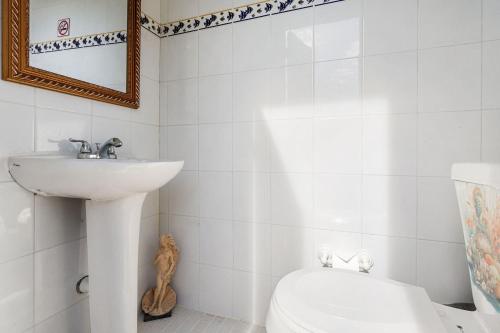 a bathroom with a sink and a toilet and a mirror at Gaviota del Mar with private pool in Rincon