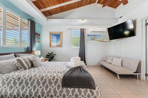 a bedroom with a bed and a couch and a tv at Gaviota del Mar with private pool in Rincon
