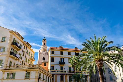 a building with a clock tower and a palm tree at Garibaldi Apartment Sanremo La Piazzetta in Sanremo
