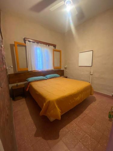 a bedroom with a yellow bed with a window at Estrella Vladimir Hostel in Capilla del Monte