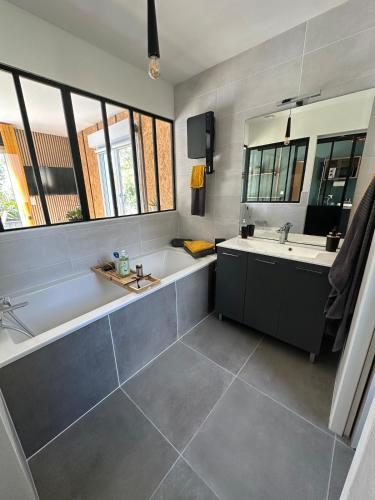 a bathroom with a tub and a sink and a mirror at Alice's Studio and Oasis in Poitiers