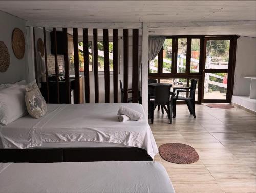 a bedroom with a white bed and a dining room at Cabañas Valle del Cocora La Truchera in Salento