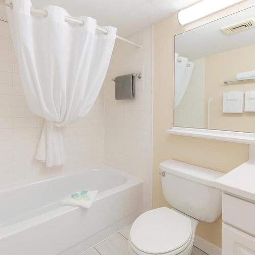a white bathroom with a toilet and a tub and a sink at Boardwalk One- Studio w Balcony and Partial Ocean View in Ocean City
