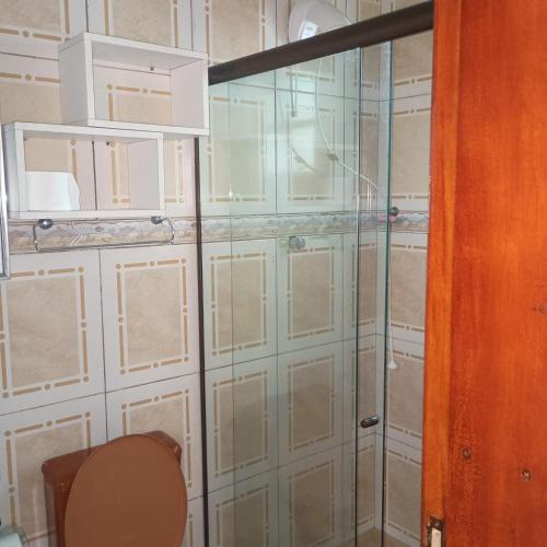 a glass shower door in a room with a toilet at Aluguel Nova Tramandaí in Tramandaí