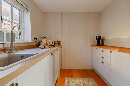 a kitchen with white cabinets and a sink and a window at 4 Bed in Westleton oc-s27303 in Westleton