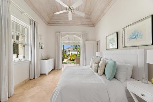 a white bedroom with a bed and a ceiling fan at Sugar Hill Resort, Bananaquit in Saint Joseph