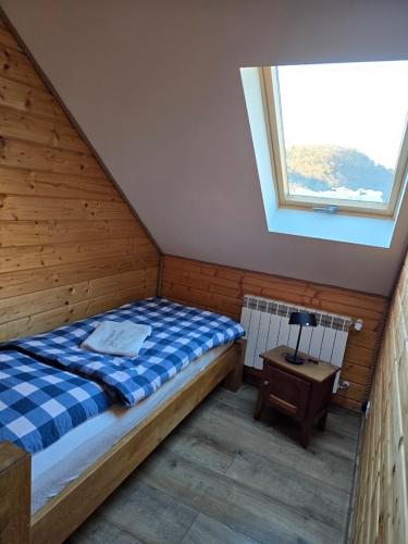 a bedroom with a bed and a window and a table at Jaśkowa Chata Bieszczady apartament z basenem nr 1i2 in Baligród