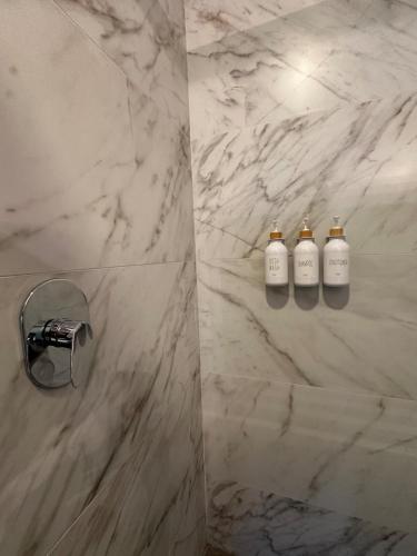 a bathroom with three shampoo bottles on a marble wall at Beautiful 2 bedrooms condo with pool Livo Tower in Monterrey