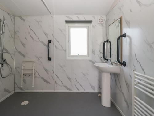 a white bathroom with a sink and a shower at Guillemot in St Bees