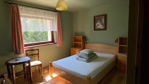 a bedroom with a bed and a window and a chair at zielonapogoda in Lądek-Zdrój