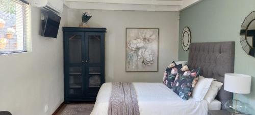 a bedroom with a bed and a black cabinet at Fevertree cottage in Bloemfontein
