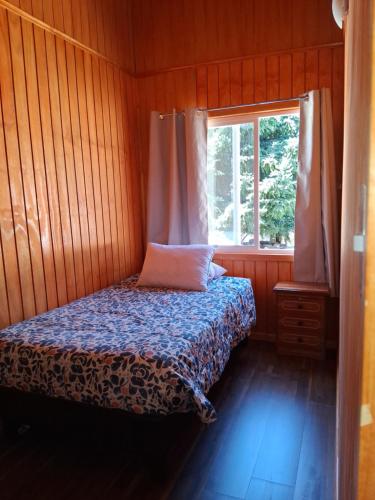 a small bedroom with a bed and a window at Mini departamento 3 in Coñaripe